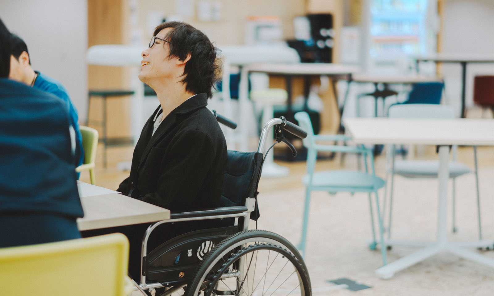 車椅子に乗り、優しく上を見上げながら、経験したことを思い出し語る近藤さん
