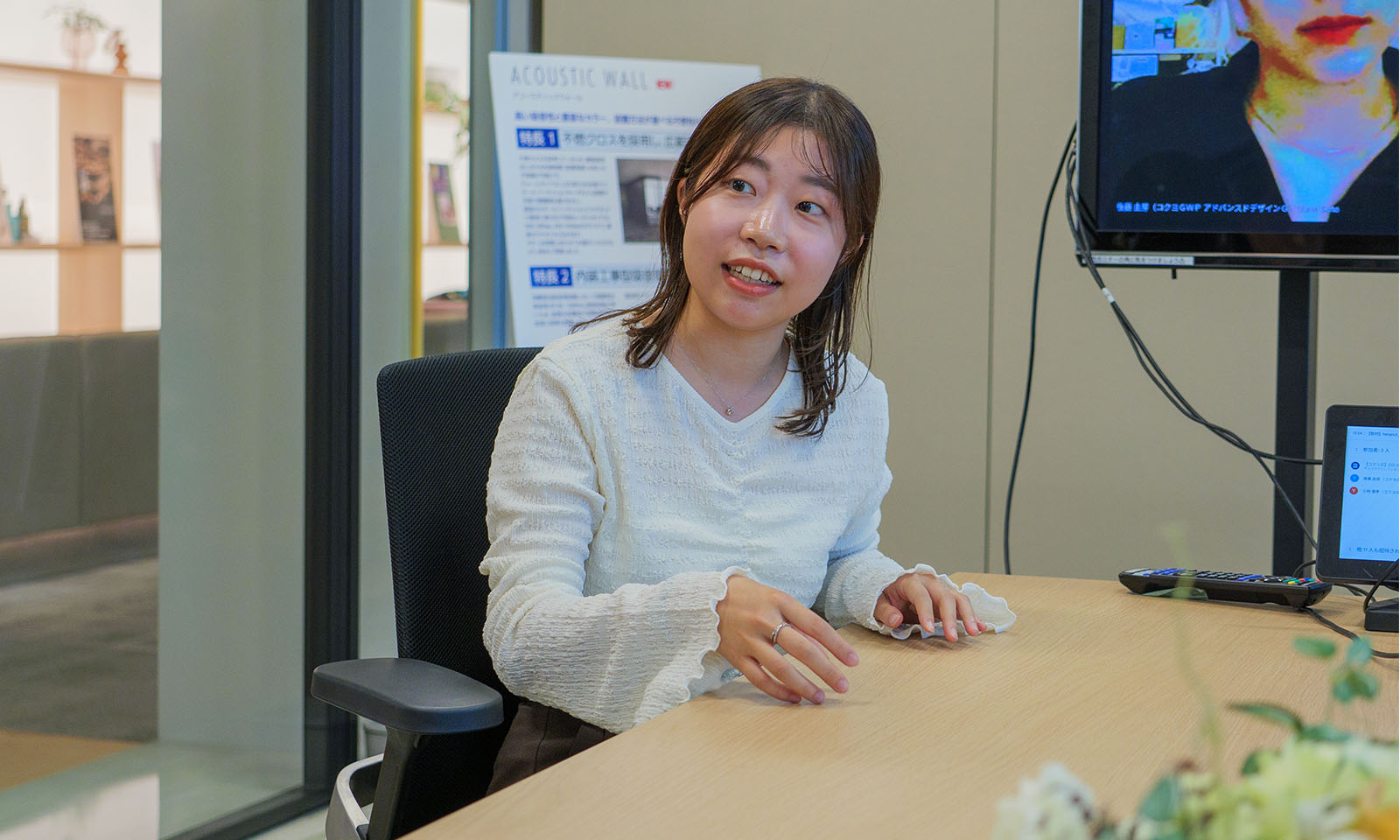 ALTはじまり。会議室の大きなテーブルに着いて話をする、袖にフリルが付いた白いニットを着たロングヘアの大塚さん。手ぶりを交えて一生懸命に語っている。ALTおわり。