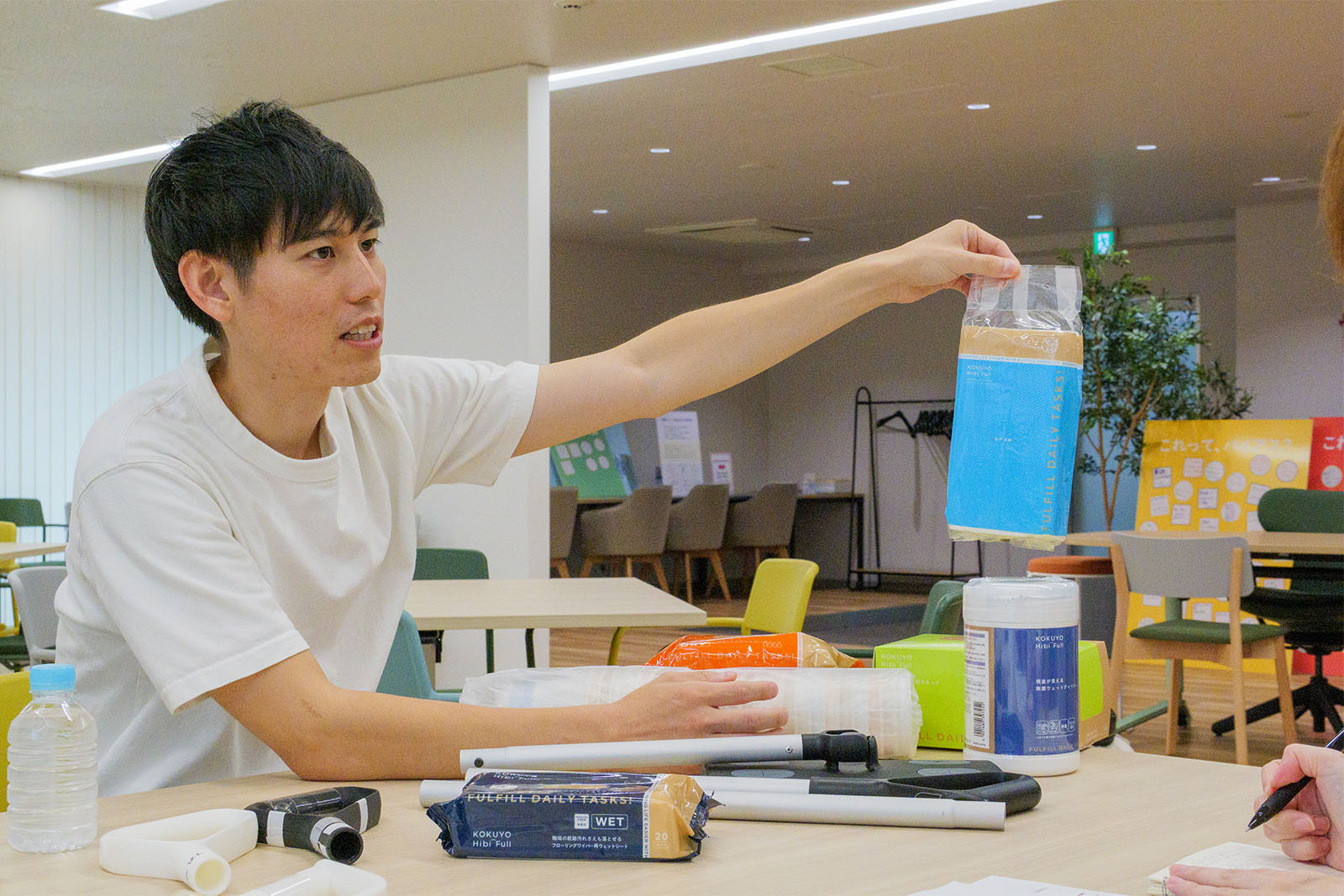 <ALT始まり>インタビュイーの大枝さんが、コクヨ　ヒビフルシリーズの「吊り下げられるキッチンペーパー」を持っている。大枝さんは白いシャツを着ている。<ALT終わり>