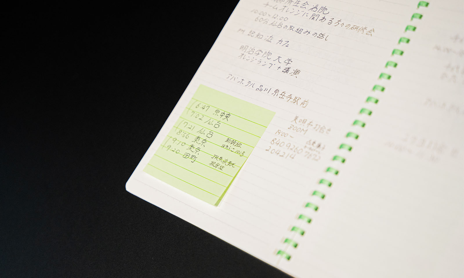 ALTはじまり。緑色のリングに罫線の入ったノート。場所と時刻がノートに書かれており、電車の乗り換え時刻表は、緑色のポストイットに書いて貼られている。ALTおわり。