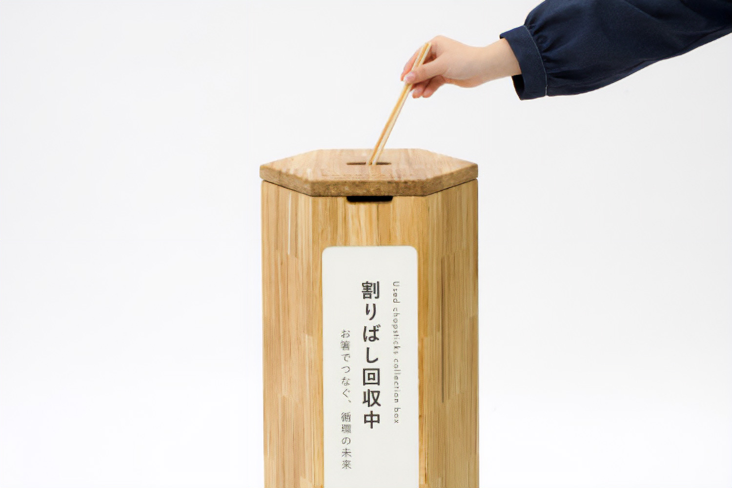 六角形の回収ボックスに割り箸を投入する様子。回収ボックス自体がチョップバリューの内装材でできている。