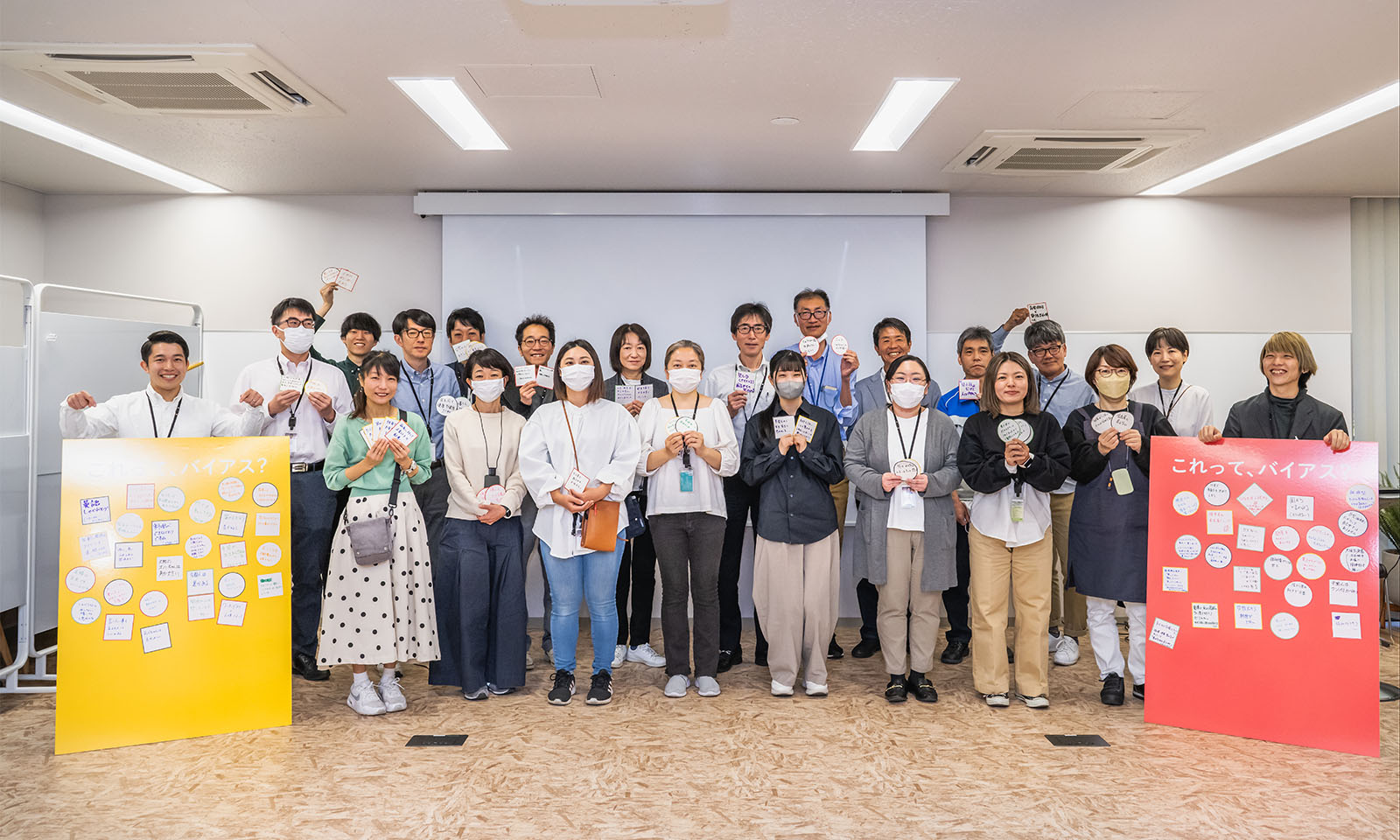 30名近くの参加者が、3列に横に並んでいる。両端にはたくさんのシールを貼ったパネル