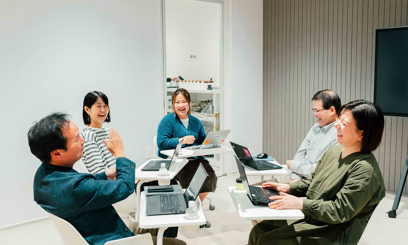 ALTはじまり。話し手となった4人と、今回ユニフォームを一緒につくったSOLIT/代表美咲が円になって話している様子。席に机が一体になった椅子で自由に動けるため、それぞれが話す動きに合わせて揺れ動いているよう。賑やかな会話と、全員が笑顔で微笑み合うことで、部屋の空気が一段と明るく感じる。ALT終わり。